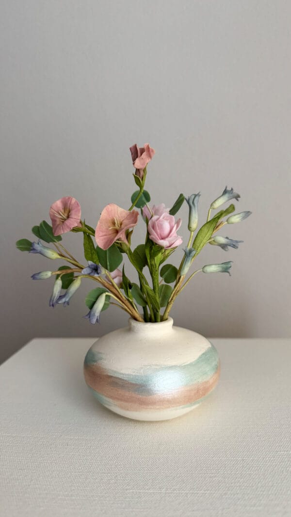 Pink morning glory and bluebells flowers in ceramic vase